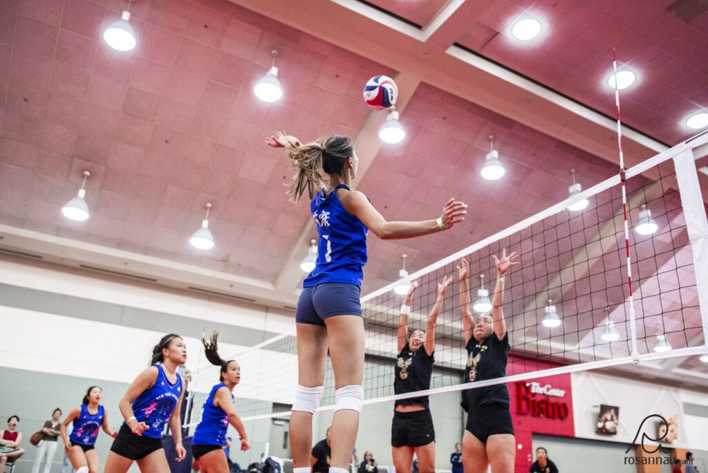 Woman jumping to hit volleyball over the net